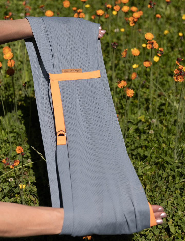 einzelner AQUA Loop in "ocean mit orangenem Ripsband", wird von zwei Händen gehalten.